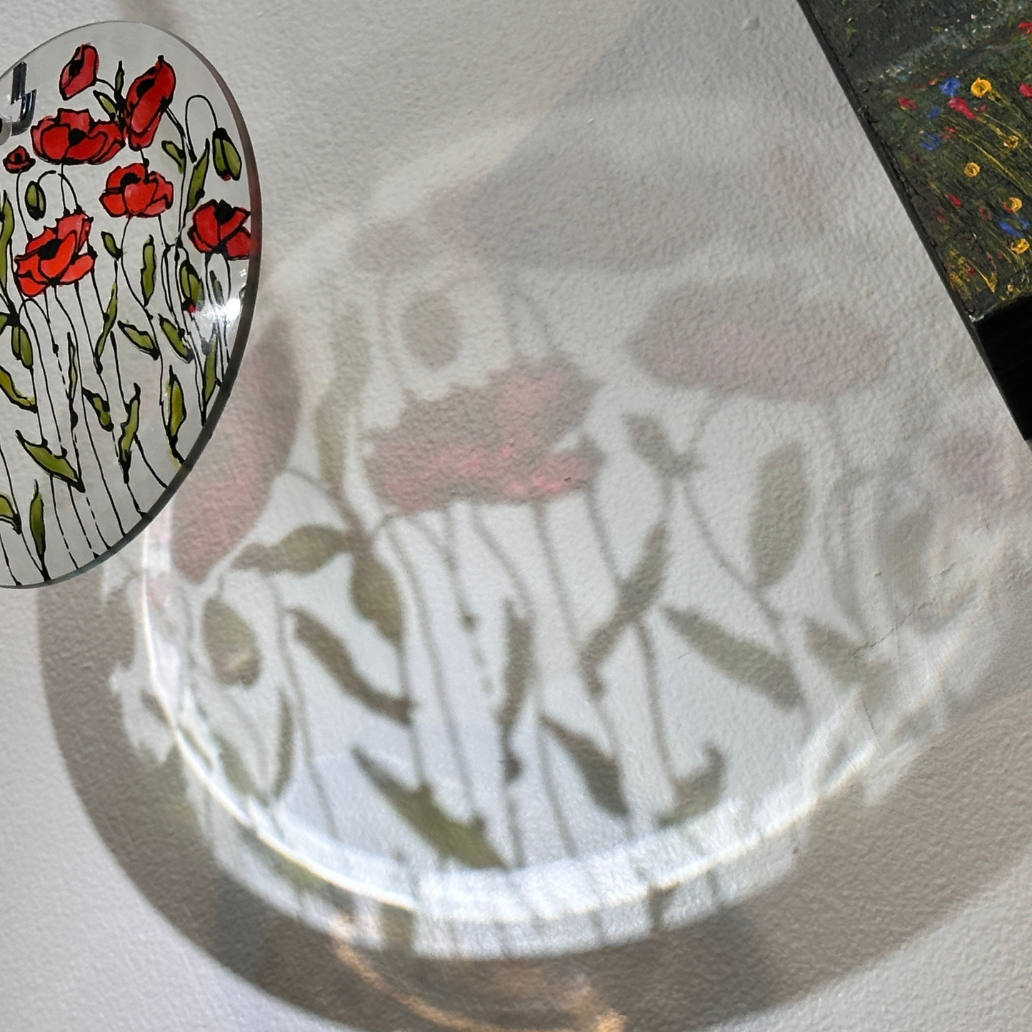 Close-up of a glass plate with floral design made during an art workshop with Sarita Kamat at Artem Pop Up Gallery, inset showing a detailed view of red flowers.