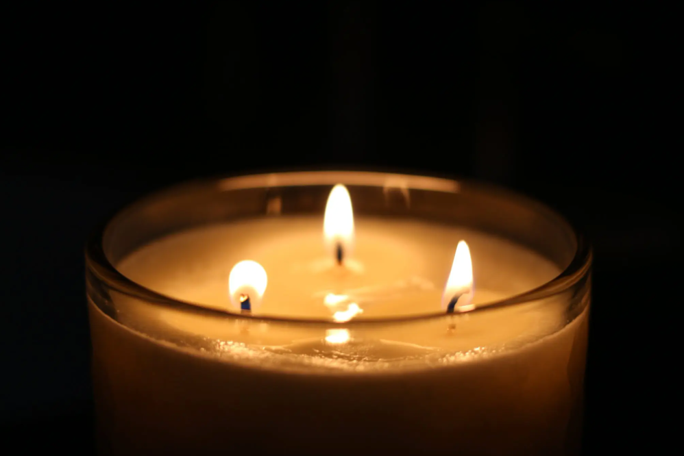 three-wick candle burning against a dark background