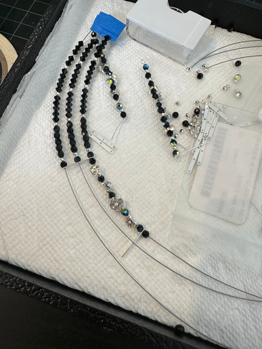 Black beaded necklace on a white surface with measurement tools