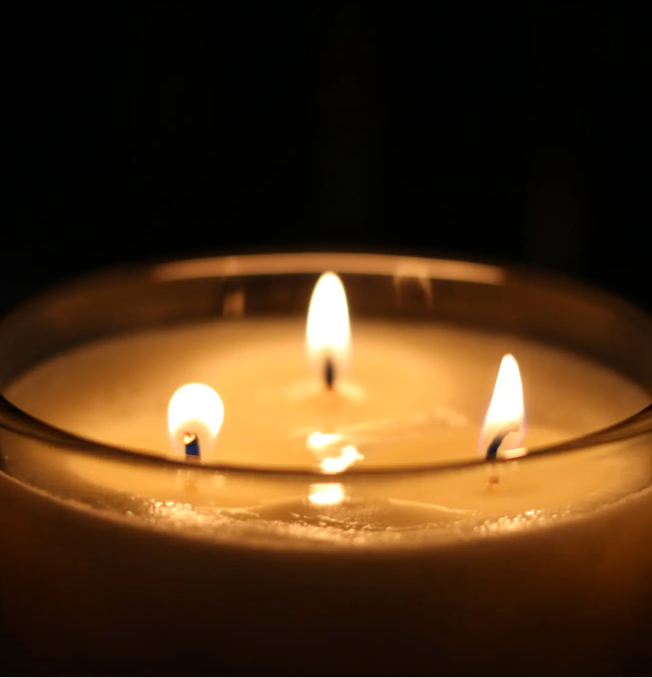 three wick candle buring against a black background