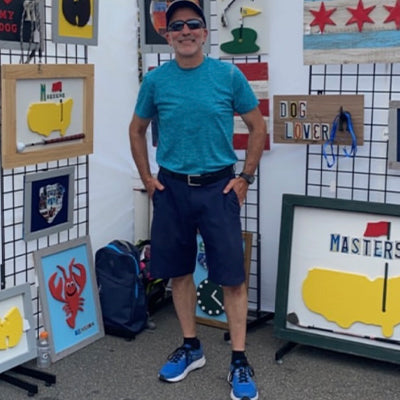 Ron Styne standing amongst his wood artwork